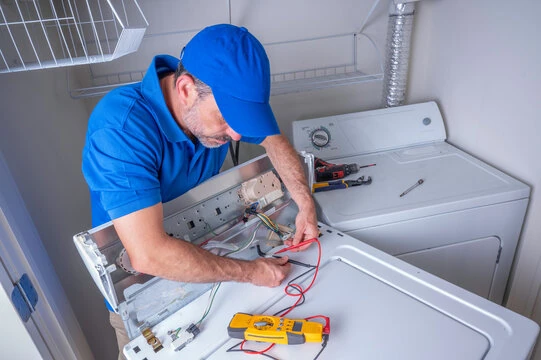 Technician testing the exposed electrical control panel of a laundry appliance